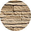 Close-up image of a beige stone wall with irregular rectangular bricks stacked in a horizontal pattern, showing a rough, textured surface. The photo is displayed within a circular frame.